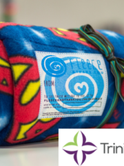 A superman blanket kit with Trinity Health logo.